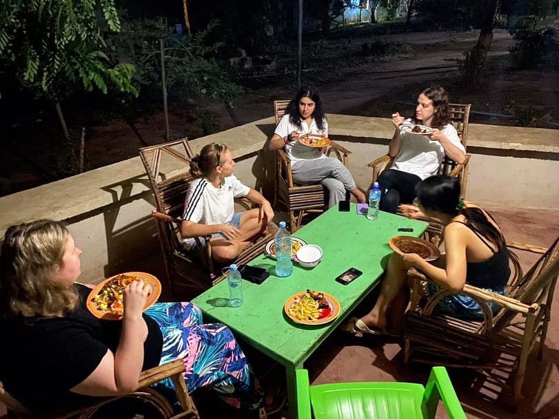A group of volunteers enjoying a meal together at a brightly colored outdoor table.