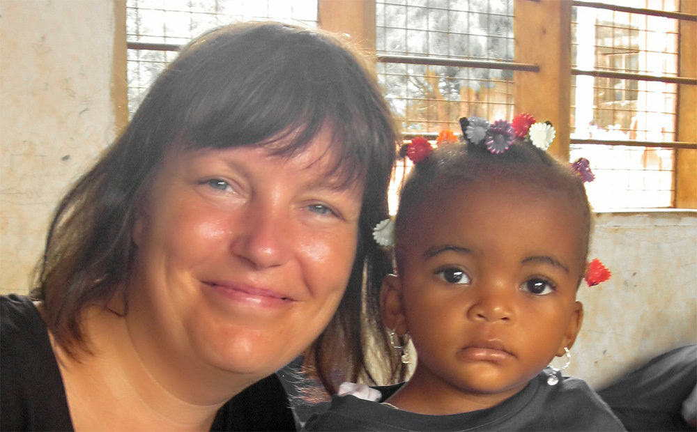 A volunteer holding a young child, highlighting the impact of social sector volunteering programs that support children and women in Tanzania.