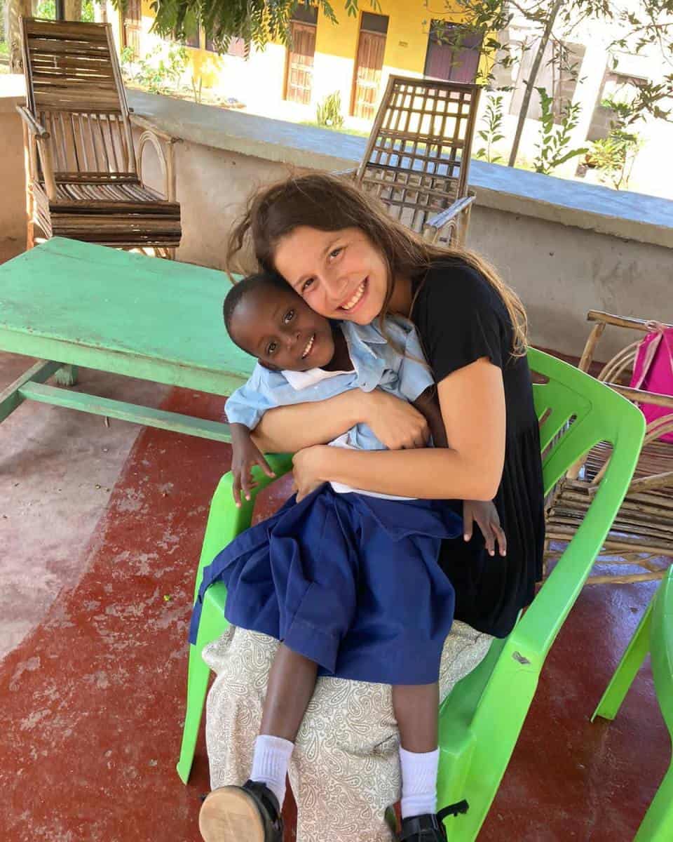 A volunteer hugging a smiling child, showcasing Green Works Africa's village education support and meaningful volunteering and internship opportunities.