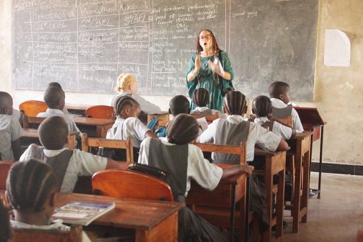 A volunteer teaching a classroom of students in a village school, representing Green Works Africa's volunteering and internship opportunities in village education and community development.
